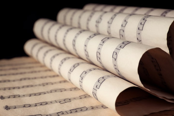 Sticker - Old wrapped sheets with music notes on black background, closeup