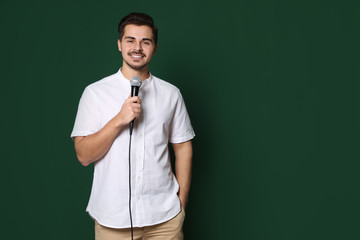 Young handsome man in casual clothes with microphone on color background. Space for text