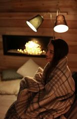 Poster - Young woman resting near decorative fireplace at home. Winter season