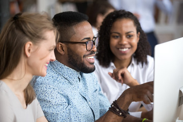 Wall Mural - Smiling african team leader explaining computer task to employees group