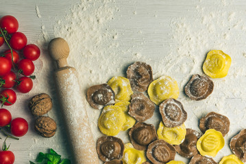 Wall Mural - Homemade fresh Italian ravioli pasta on white wood table  with flour, basil, tomatoes,background,top view.