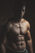 © alfa27 - Attractive African male fighter or boxer posing shirtless, looking at camera, isolated over dark background.
