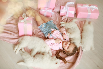 Little girl with white puppies and gift boxes