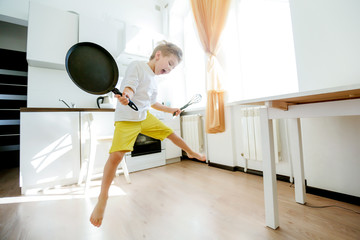 funny European little boy chef dancing,Happy weekend, boy wants to make pancakes, but the frying pan are too gay, he decided to have fun holding wooden spoons in his hands, having fun while cooking