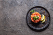 Raw salmon, avocado purple onion salad served in culinary ring on black plate. Black concrete background