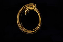 Long Exposure, Light Painting Photography.  Letter O In A Vibrant Neon Metallic Yellow Gold Colour Against A Black Background.  Alphabet Series.