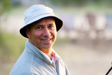 Portrait, close up of a caucasian fisherman, 50's, at the lake with fog, early morning just before sunrise.