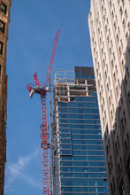 Large Red Crane Running Up The Side Of A Skyscraper With Buildings On The Sides