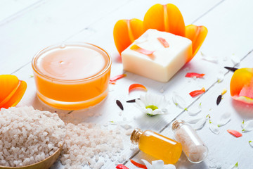 aromatherapy: orange gel and extract, bath salt, cosmetic cream, organic soap and petals on white wood