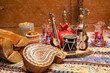 The Holiday Of Navruz.Small figures of national musical instruments: tar, drum on a wooden stand, on the background of tea glasses in the form of pears, old painted jugs and brown wooden wall.