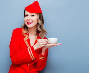 stewardess wearing in red uniform with cup of coffee or te