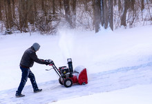 Man Using Snowblower To Clear An Uphill Driveway