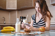 © Artem - Woman drinking organic almond milk holding a glass in her hand in the kitchen. Diet healthy vegetarian product