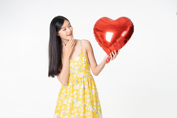 Asian young woman in yellow dress hold  red balloon heart. Young woman holding it with  being excited and surprised  holiday present isolated white  background.concept love surprise valentine day.