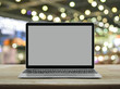 © grapestock - Modern laptop computer with blank grey screen on wooden table over blur light and shadow of shopping mall