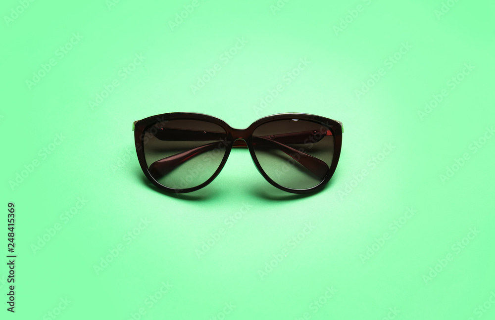 Stylish sunglasses on color background