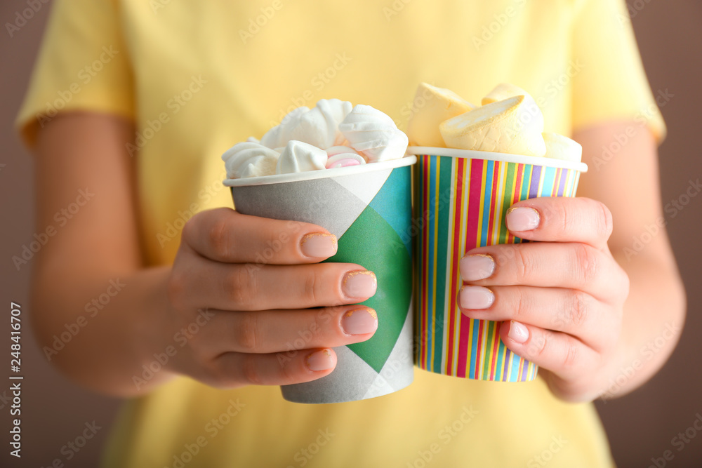 Young woman holding cups with tasty marshmallows, closeup