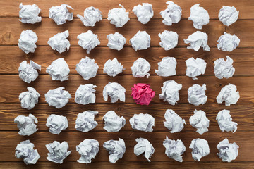 Concept of creativity and inspiration presented by many white paperballs and one color