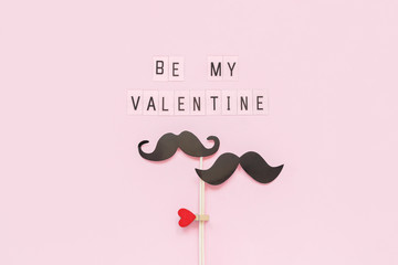 Couple paper mustache props on stick fastened clothespin heart and text Be my Valentine on pink background Concept Homosexuality gay love. Valentine's Day, Valentine card Creative Top view