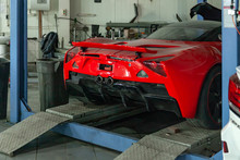 Red Sports Car Raised On A Lift In A Car Repair Shop, Rear Bumper And Spoiler