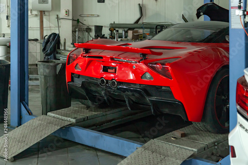 Cuadros en Lienzo Red sports car raised on a lift in a car repair shop, rear bumper and spoiler