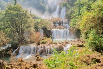  Thi Lo Su Waterfall (Umphang), beautiful silky water flowing from top of green mountain around with green forest and blue sky background, the largest waterfall in Thailand, Umphang, Tak, Thailand.