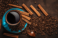 Cup Of Aromatic Black Coffee, Coffee Beans And Cinnamon Sticks On Dark Background. Still Life.