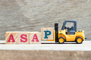 Wall Mural - Toy forklift hold letter block p to complete word asap (abbreviation of as soon as possible) on wood background