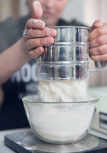 A Woman Sieving White Baking Flower Making It Into A Fine Refined  Batch, Preparing For Baking Cake Recipe. Metal Flour Serving.