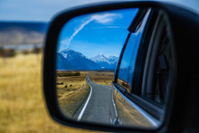 Roadtrip/car Traveling Concept. View Of Back Car Mirror With Mountain And Road Scenery. Aoraki/Mount Cook National Park, South Island Of New Zealand.