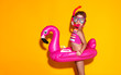 © JenkoAtaman - happy child girl in swimsuit with swimming ring flamingo on colored yellow background
