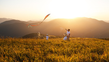 Happy family father and children launch  kite on nature at sunset.