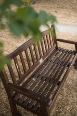 A beautiful dark brown rustic weathered wooden hand made bench, photographed from above. Bench in in a dry summer park setting. Photographed with a shallow depth of field.