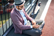 © baranq - Stylish man sitting outdoors on sunny day and using tablet
