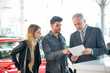 © Minerva Studio - Happy young family talking to the salesman in a car showroom