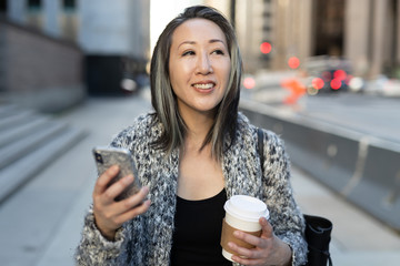 Wall Mural - Asian woman in city walking texting cell phone