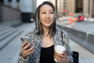 Wall Mural - Asian woman in city walking texting cell phone