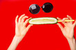 © Leart - Women hand holding cucumber. Funny summer background making face with cucumber and sunglasses isolated over red background