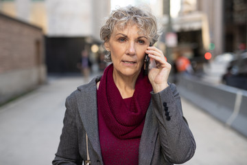 Sticker - Mature woman in city walking talking on cell phone