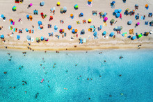 Aerial View Of Sandy Beach With Colorful Umbrellas, Swimming People In Sea Bay With Transparent Blue Water At Sunny Day In Summer. Travel In Mallorca, Balearic Islands, Spain. Top View. Seascape