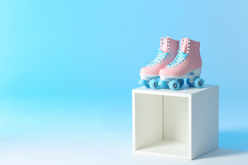 Wall Mural - pair of vintage roller skates on storage cube against color background. space for text