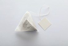 Unused Pyramid Tea Bag With Tag On White Background, Top View. Space For Text
