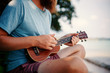 Young handsome redhead man with a beard playing a ukulele on a tropic beach, music, art, travel and vacations concept