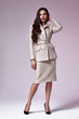 © indiraswork - Beautiful woman lady spring autumn collection glamor model business office fashion clothes wear casual style beige color suit blouse jacket skirt pretty face dark hair background studio.