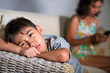 © TheVisualsYouNeed - young sad and bored Asian child at home couch feeling frustrated and unattended while mother networking on mobile phone as internet addict neglecting her son