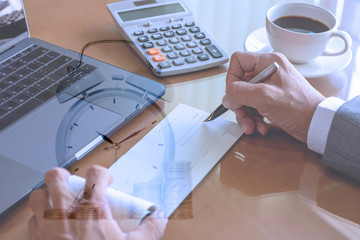 Wall Mural - Business man in suit,  hand writing and signing checkbook with calculator and tablet computer on the desk at office.