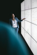 © JonoErasmus - Black african businesswoman giving a presentation at a business conference. Looking at a large video screen with charts and graphs next to her in a dark room