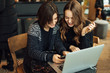 © Serhiy Hipskyy - Two girls, friends Drink Hot Coffee While Work In Cafe On Laptop. Portrait Of Stylish Smiling Girls In Winter Clothes Drinking Hot Coffee And Work At Laptop. Female Winter Style. - Image