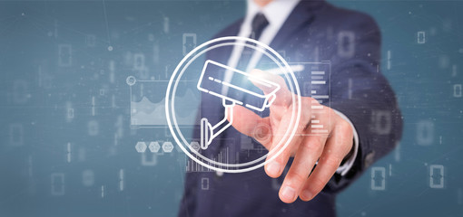 Poster - Businessman holding Security camera system icon and statistics data - 3d rendering