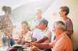 © simona - Cheerful different ages people stay together for lunch and drinking wine having a lot of fun - group of caucasian people laughing - mature adult and young - sunny backlight  - food and drinks